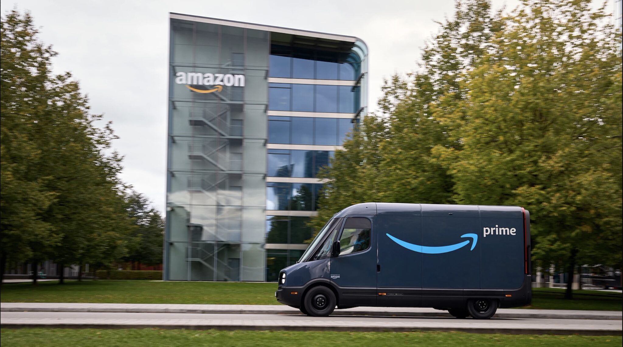 An Amazon Prime electric delivery van on the road outside an Amazon facility